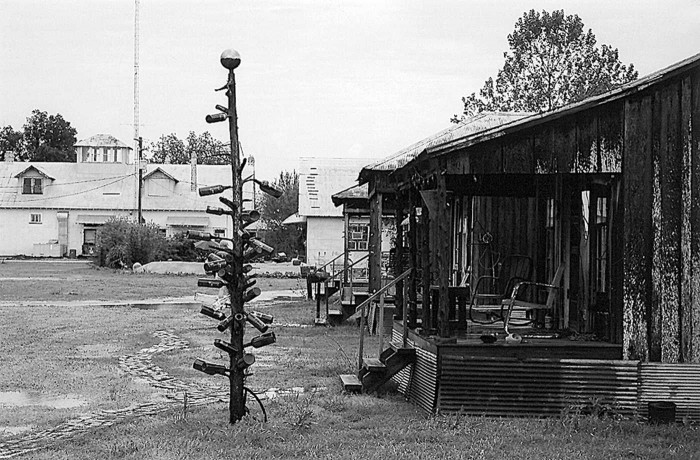 Hopsova plantācija netālu no Klārksdeilas, kur tūristi par samērā lētu naudu var pārgulēt kādreizējās laukstrādnieku būdiņās. Zilās pudeles ir autentiska detaļa — tādās melnie būdiņu iemītnieki kādreiz ķēra ļaunos garus, lai tie viņiem neko nenodarītu